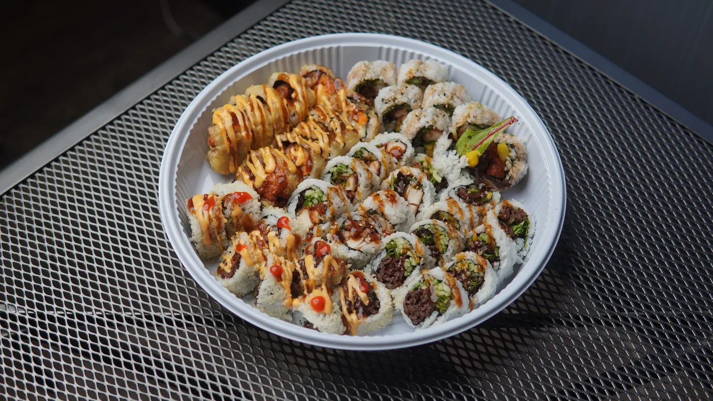 A round catering platter of sauced sushi rolls